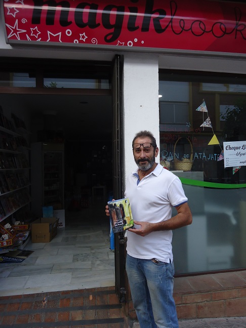 Rogelio Romero, en la entrada de Magik Books, con un ejemplar de Un paseo por Ronda.